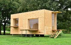 a small wooden structure sitting on top of a lush green field next to lots of trees