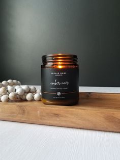 a candle sitting on top of a wooden tray next to some white flowers and cotton balls