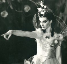 a black and white photo of a woman dressed as a fairy with her arms outstretched