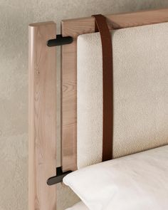 a bed with a wooden headboard and white sheets on it's sides, hanging from the wall