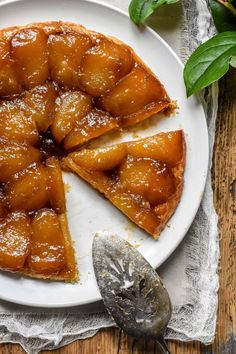 a pineapple upside down cake on a white plate next to a fork and spoon