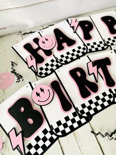 two happy birthday signs are sitting on a table with pink and black checkered paper