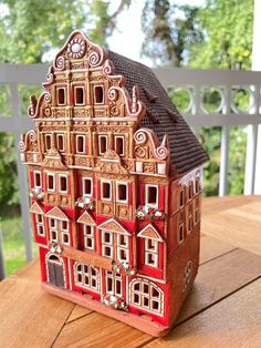 a red and brown doll house sitting on top of a wooden table