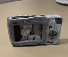 a small toy television with a face on it's screen and an image of a woman behind the screen