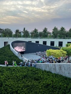 a crowd of people standing on top of a lush green hillside next to a building