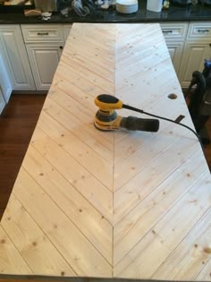 a cordless sanding machine is on top of a wooden planked countertop