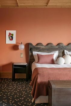 a bed sitting in a bedroom next to a wall with paintings on it and two lamps