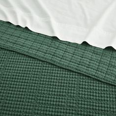 a green quilted bed spread with white sheets