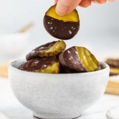 a person is dipping some kind of chocolate into a bowl with other food items in the background