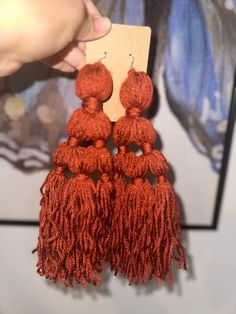 a pair of red tasselled earrings hanging from a card