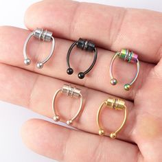 four different types of piercings on someone's finger in their hand, one is gold and the other is silver