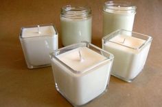 four glass containers filled with candles on top of a table