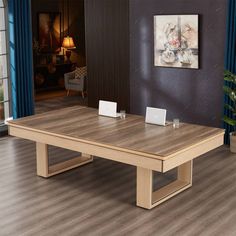 a large wooden table sitting on top of a hard wood floored floor next to a blue curtain