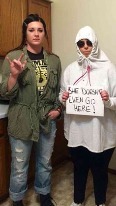 two people in costumes standing next to each other and holding signs that say she doesn't even go here