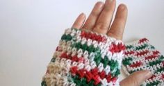 a woman's hand is wearing a crocheted mitt with red, green and white stripes