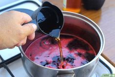 someone is pouring something into a pot on the stove with red liquid being poured over it