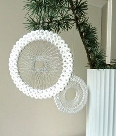 a white ornament hanging from a pine tree