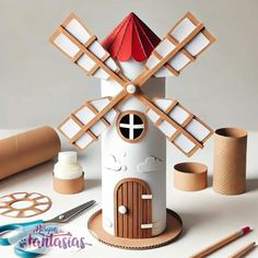 a paper model of a house with a windmill on top and other crafting supplies around it