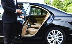 a man in a suit getting out of a car with his hand on the door