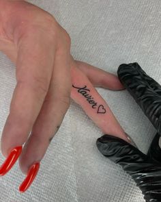 a woman with red nails and black gloves on her fingers has a small tattoo that reads, i love you