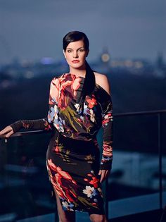 a woman standing on top of a balcony next to a railing with her hands on her hips