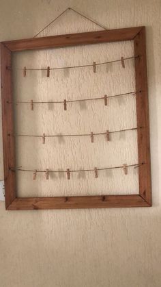 a wooden frame with clothes pins hanging from it's sides in front of a wall