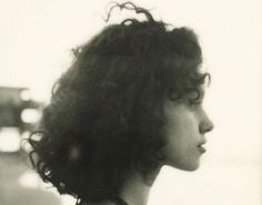 a black and white photo of a woman with curly hair looking off into the distance