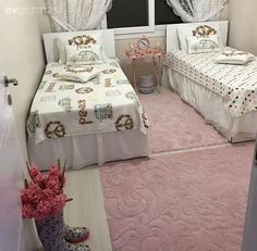 two twin beds in a small room with pink rugs and white curtains on the windowsill