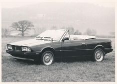 a black and white photo of a car parked in the grass