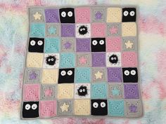 a crocheted blanket with eyes and stars on it