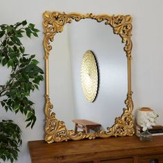 a mirror sitting on top of a wooden dresser next to a potted green plant