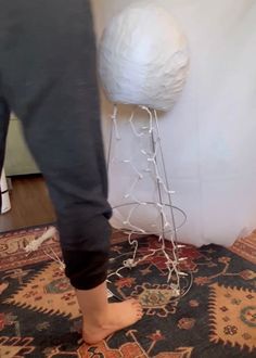 a person standing next to a white ball on top of a rug