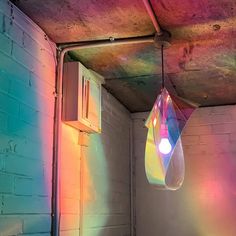 a colorful light shines on the ceiling in a room with exposed concrete and brick walls