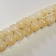 two strands of yellow jade beads on a white surface