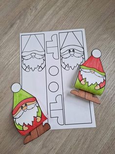 two wooden pegs are sitting on top of a paper cut out of santa claus