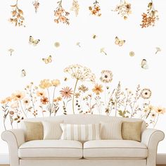 a couch sitting in front of a white wall with flowers and butterflies flying above it