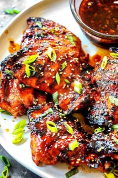 chicken wings with sauce and green onions on a white plate