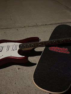 an electric guitar laying on the ground next to a skateboard