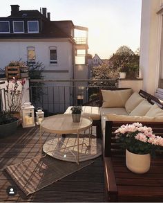 a balcony with furniture and potted flowers on the table in front of the window