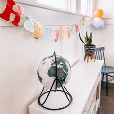 a birthday banner with the words happy birthday hanging on a wall above a desk and chair