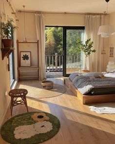 a bedroom with wooden floors and large windows overlooking the trees in the distance is furnished with natural wood flooring