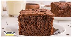 a piece of chocolate cake on a plate with a fork and glass of milk in the background