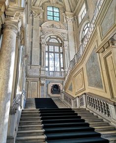 an ornate staircase with black steps leading up to the second floor and windows above it