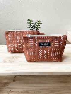 two brown bags sitting on top of a table next to a small potted plant