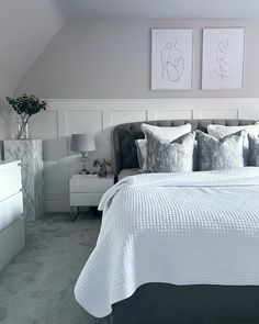 a white bed sitting in a bedroom next to two pictures on the wall above it