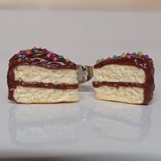 two pieces of cake with chocolate frosting and sprinkles on them sitting on a white surface