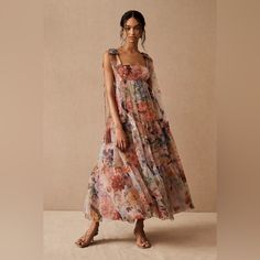 a woman in a floral dress poses for the camera