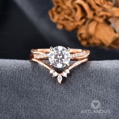 a close up view of a diamond ring on top of a cushioned surface with a rose in the background