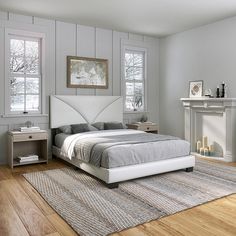 a white bed sitting on top of a wooden floor next to a fireplace in a bedroom