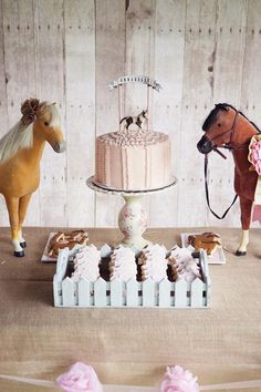 a table topped with cakes and toy horses